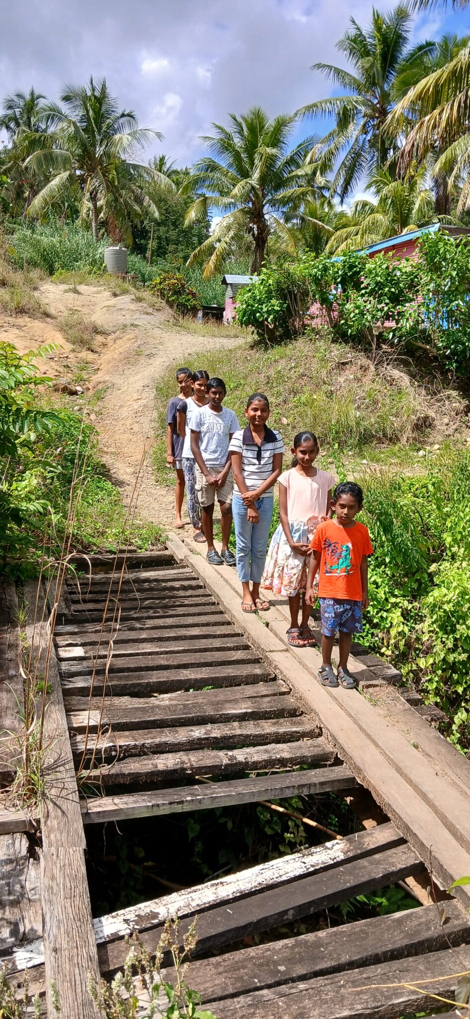 group of children stands next to dilapidated footbridge