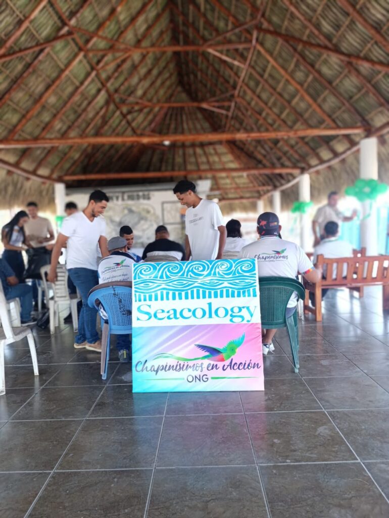 A sign with the Seacology logo in a building with a thatched roof