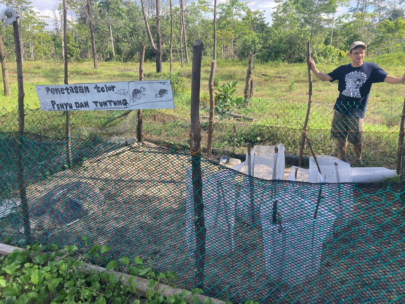 A person stands next to a turtle enclosure
