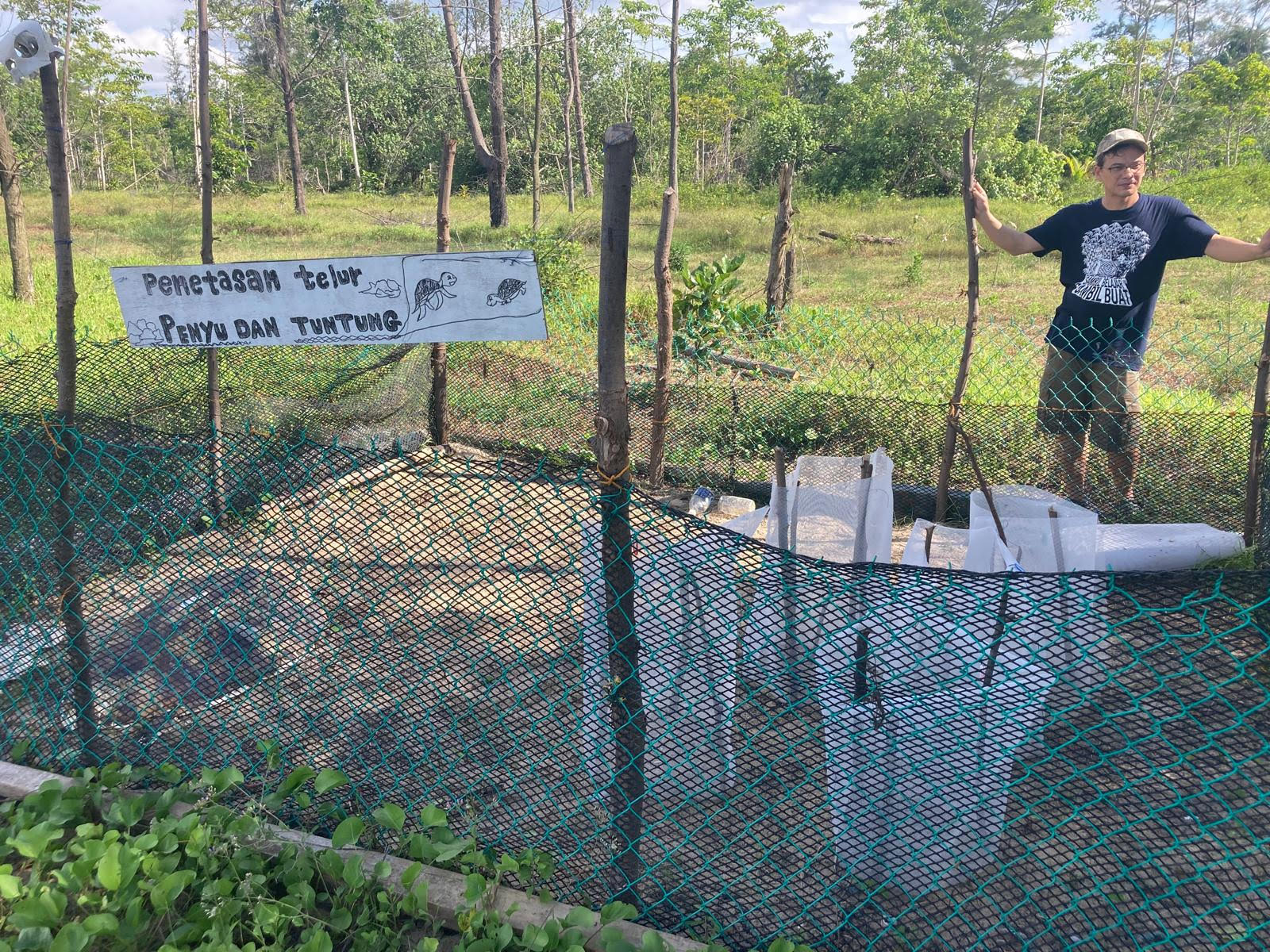 A person stands next to a turtle enclosure