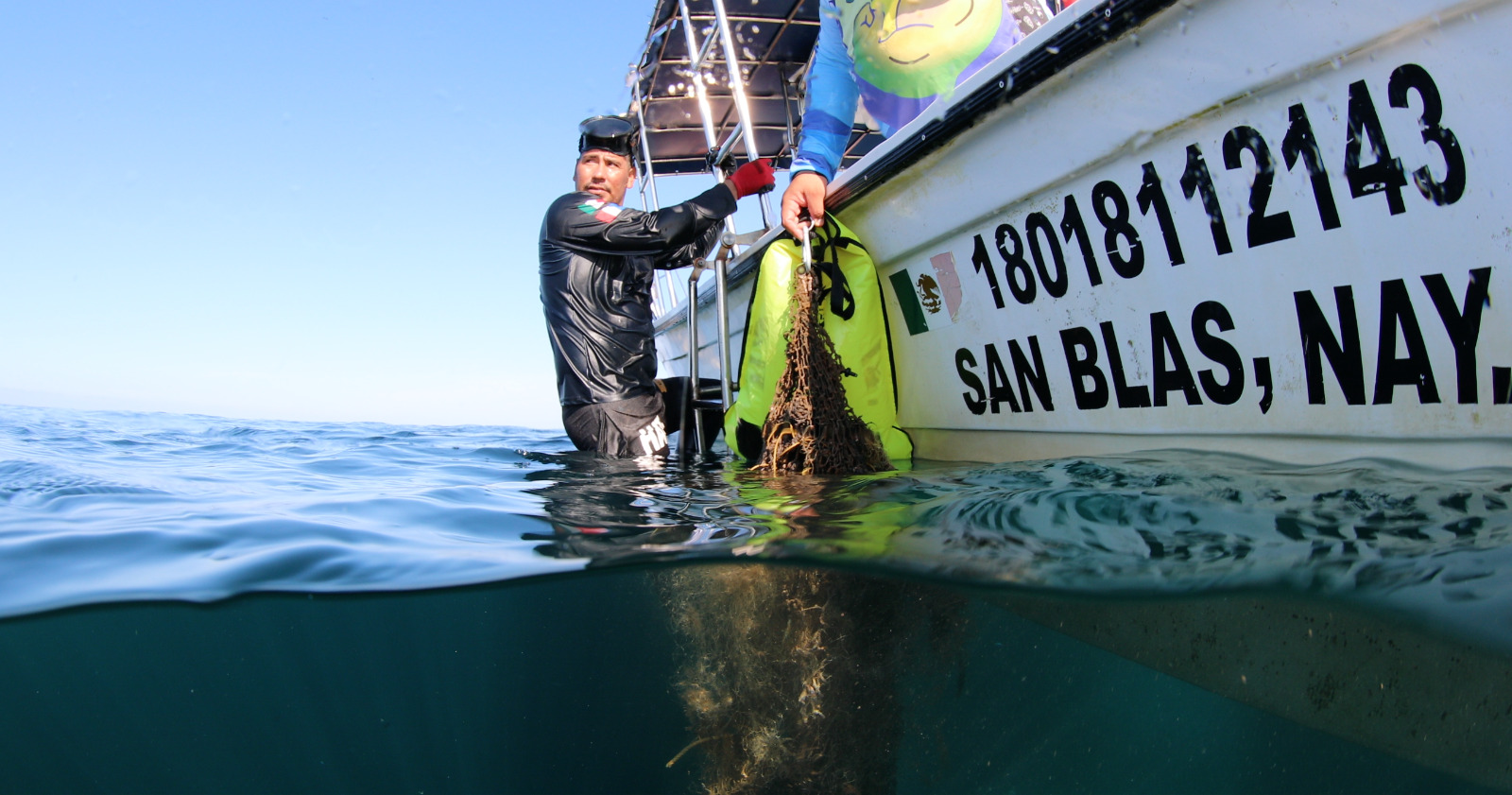 Diver hanging off the side of a boat