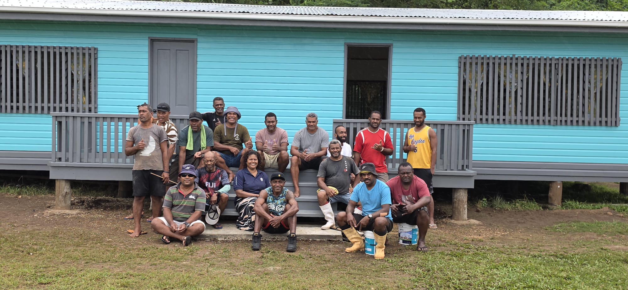 Men stand in front of new building painted bright blue.