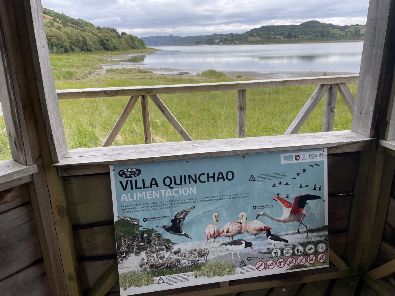 A sign reading "Villa Quinchao" on a viewing deck overlooking a lake