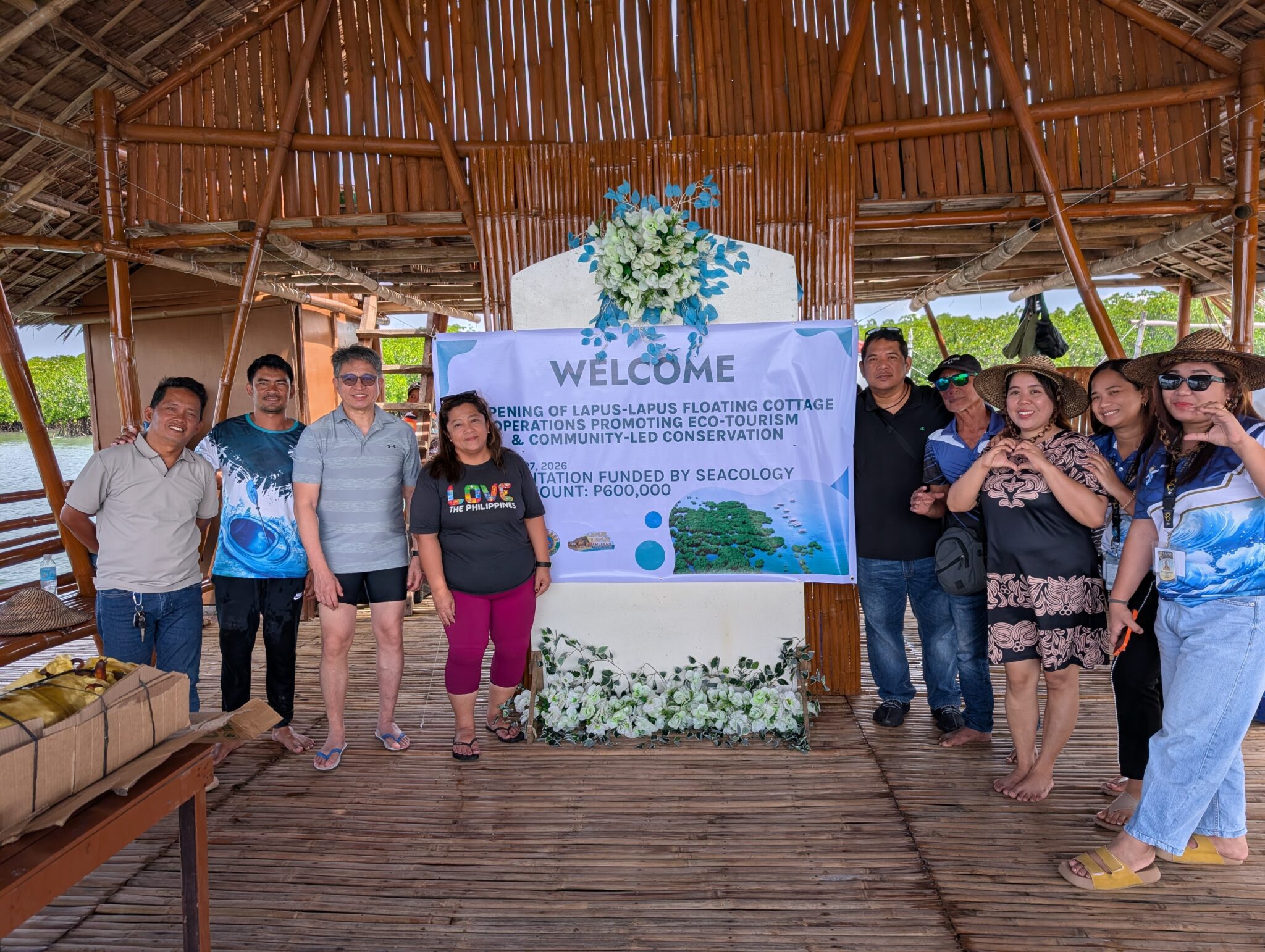 A group of people pose with a "welcome" sign
